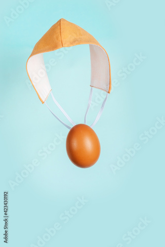 Brown chicken egg with pink fabric medical mask as a parachute