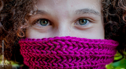 Girl's face portrait partially covered by crochet accessory 