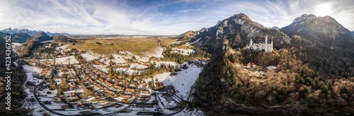 360 Aerial panorama drone shot of picturesque Neuschwanstein Castle on snowy hill in winter sunlight in Germany photo
