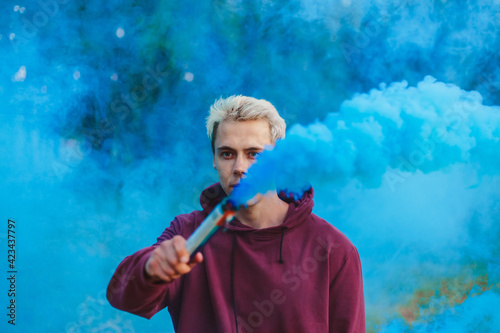 Street style man in hoodie hold hand flare with red smoke grenade bomb. photo