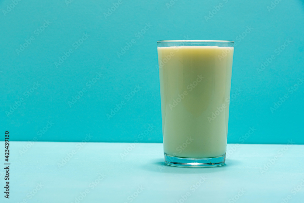 Glass cup with milk on blue background Glass cup with milk on blue background
