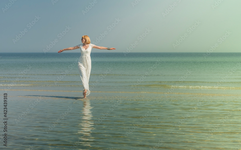 beautiful woman in sunglasses stands and poses in the sea in a white wedding dress beautiful woman in sunglasses stands and poses in the sea in a white wedding dress