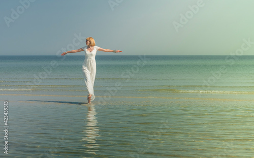 beautiful woman in sunglasses stands and poses in the sea in a white wedding dress