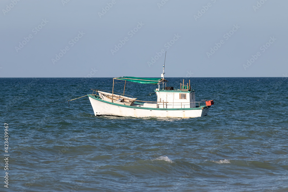 Small white fishing boat floating in the ocean - fisherman out to sea to support his family. Yucatan, Mexico