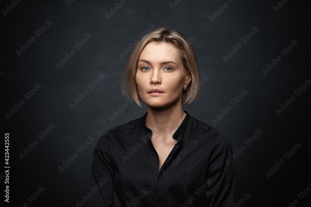 Beautiful middle-aged woman on a gray background in a black blouse.