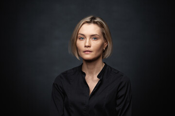 Beautiful middle-aged woman on a gray background in a black blouse.