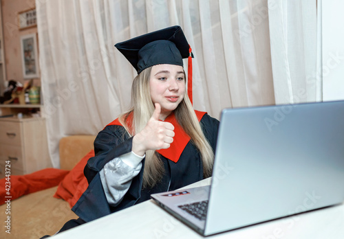 Virtual graduation and convocation ceremony. Excited student wearing graduation gown and cap talking with her family and receiving congratulation during online video call, distant education