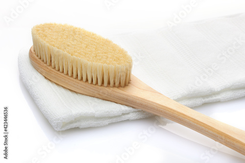 A dry massage brush made of natural materials and a cotton towel on a white background. Cleanliness and body care concept