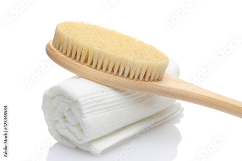 A dry massage brush made of natural materials and a cotton towel on a white background. Cleanliness and body care concept