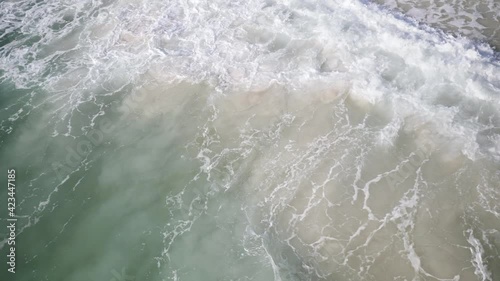 Emerald coast ocean waves rolling onto a white sand beach