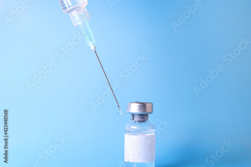 Doctor holding vial with vaccine against Covid-19 on light background, closeup. Coronavirus Vaccine / Corona virus Vaccine concept with syringe. Vaccine Concept of fight against coronavirus. 