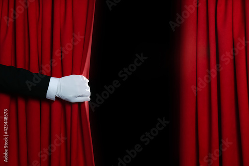 Person opening red front curtains on black background, closeup