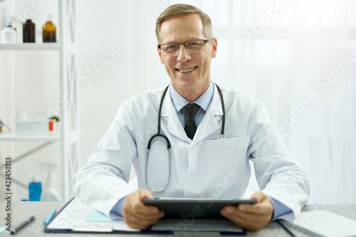 Cheerful male doctor using tablet computer at work