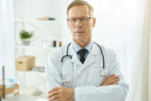Handsome male doctor in lab coat standing in clinic