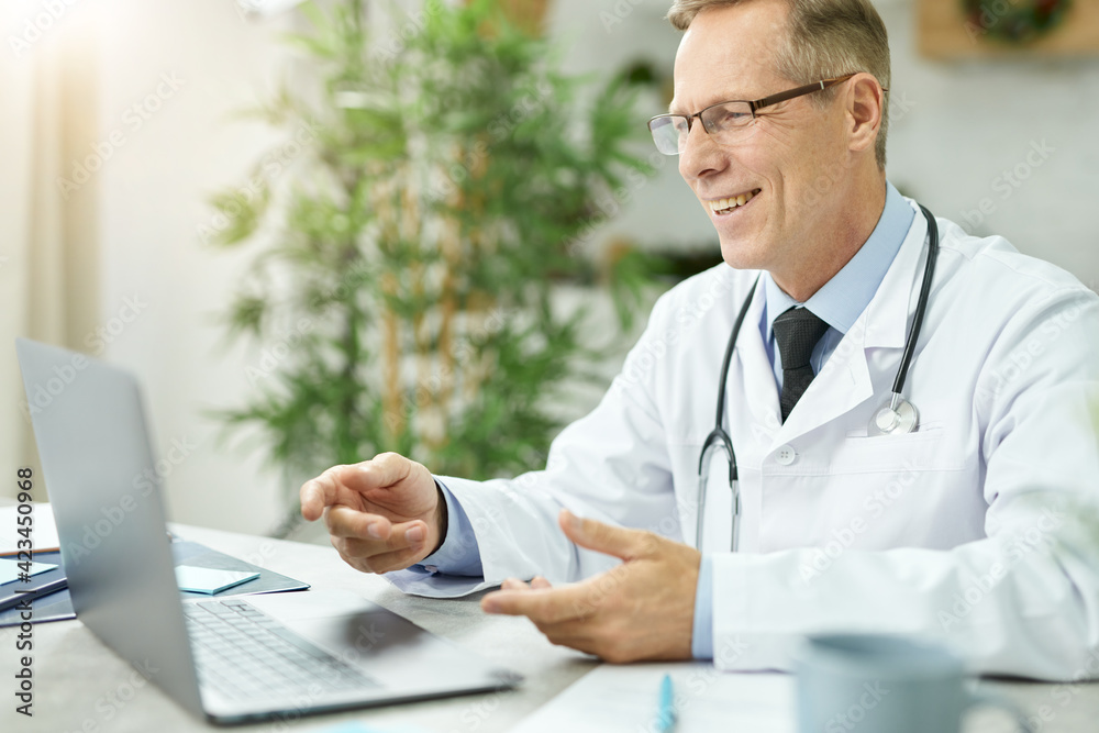 Cheerful male doctor using modern notebook in clinic Cheerful male doctor using modern notebook in clinic