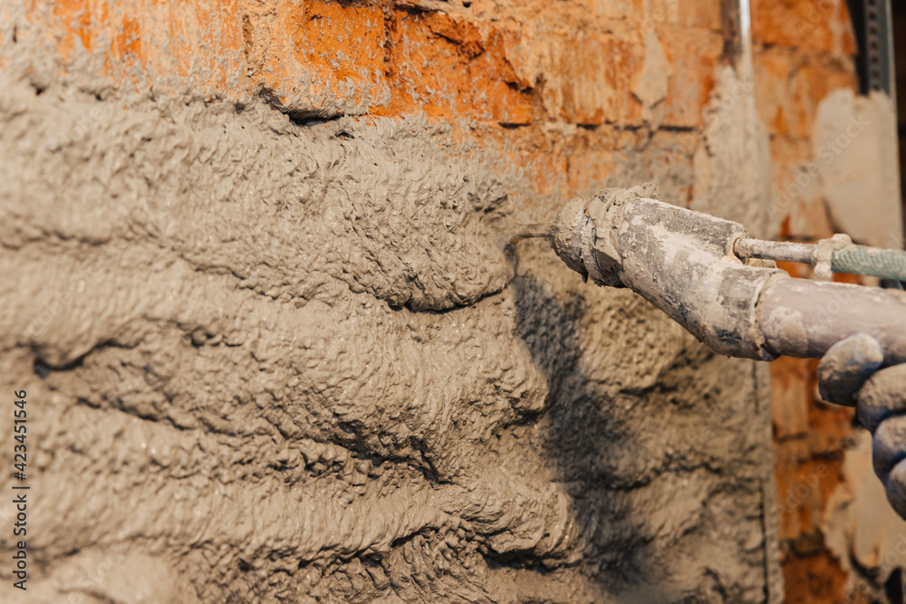 Obraz premium Semi-automatic wall plastering process. The plaster solution is thrown out of the sprayer onto the wall.