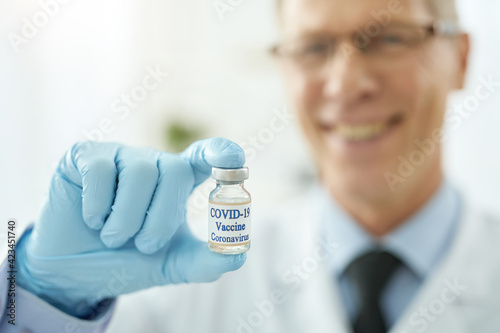 Male doctor hand in sterile glove holding covid-19 vaccine
