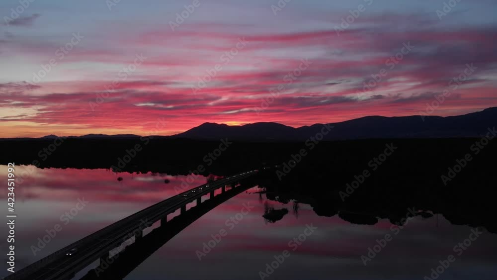 Toma aérea de un atardecer sobre un puente del Norte de Madrid, junto a un embalse grabado en 4k desde un dron