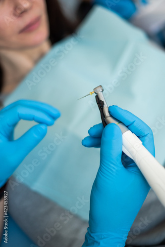 The dentist's tools are in his hands. Blue gloves.