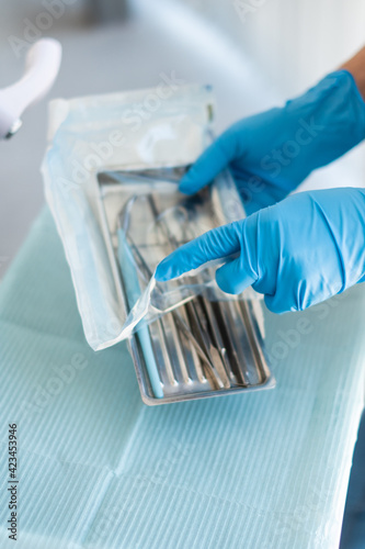 The dentist's tools are in his hands. Blue gloves.