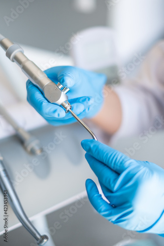 The dentist's tools are in his hands. Blue gloves.