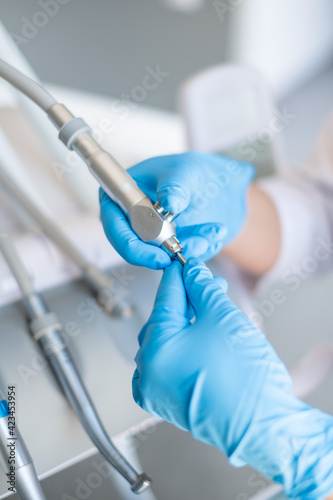 The dentist's tools are in his hands. Blue gloves.