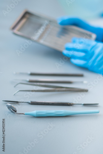 The dentist's tools are in his hands. Blue gloves.