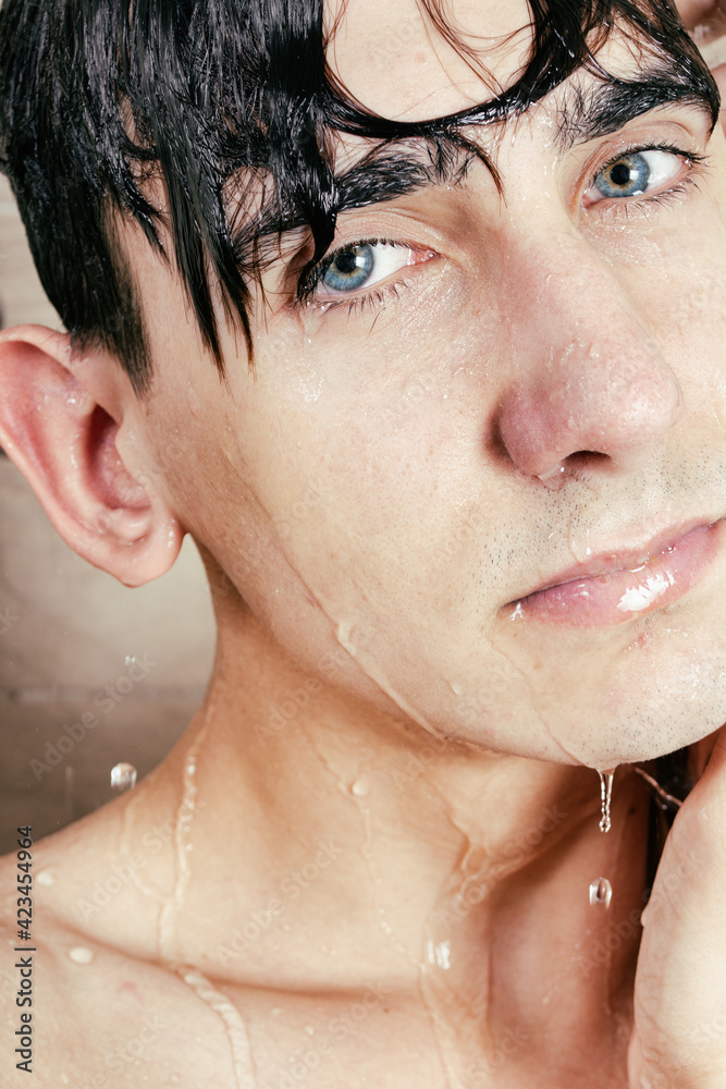Naklejka premium The athletic guy takes a shower. Body care and hygiene. Foam on the head.