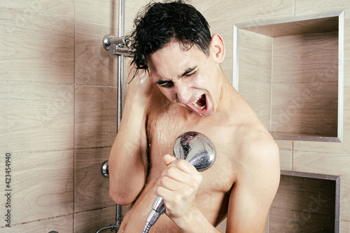 The funny guy is singing in the shower. Parodies and makes grimaces. Athletic body in the water. Bath procedures. Care and hygiene.