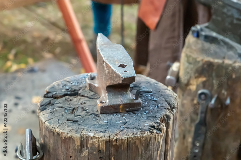 iron anvil traditional on a wooden deck on a blurred forge background iron anvil traditional on a wooden deck on a blurred forge background