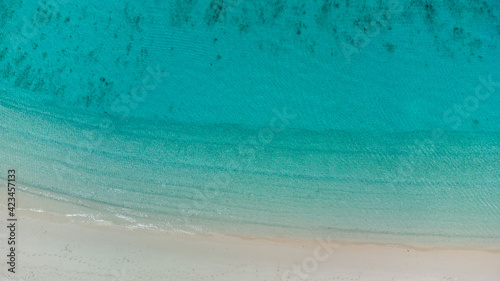美しいケラマブルーの海と砂浜に白波が立つドローン俯瞰写真
