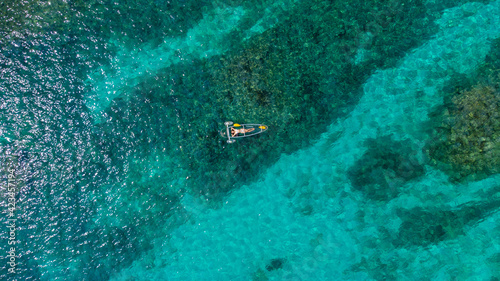 サンゴ礁が透けるケラマブルーの海にクリアカヤックで浮かぶドローン俯瞰写真 © NinjaTech LLC