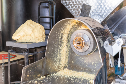 front view of a nixtamal mill while a man takes out the dough that is being produced