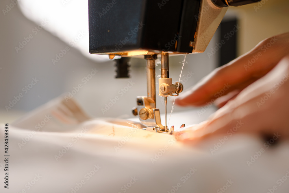Close up on hands of unknown woman sewing on electric sewing machine