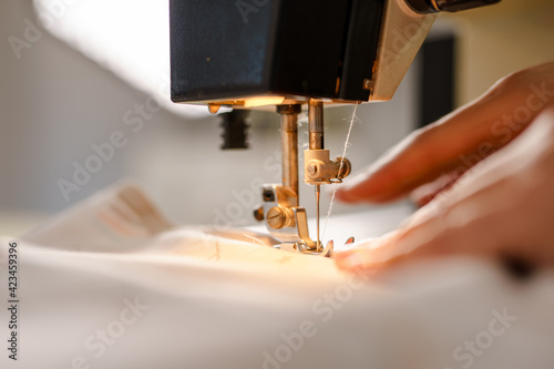 Fototapeta Close up on hands of unknown woman sewing on electric sewing machine
