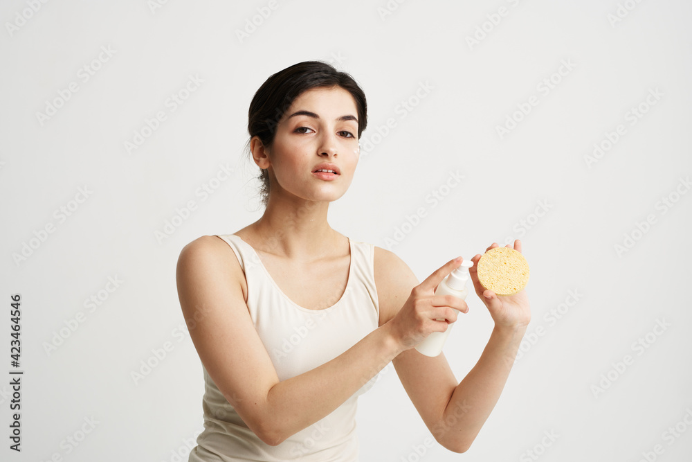 Beautiful brunette in a white T-shirt Sponge in the hands of skin care Beautiful brunette in a white T-shirt Sponge in the hands of skin care