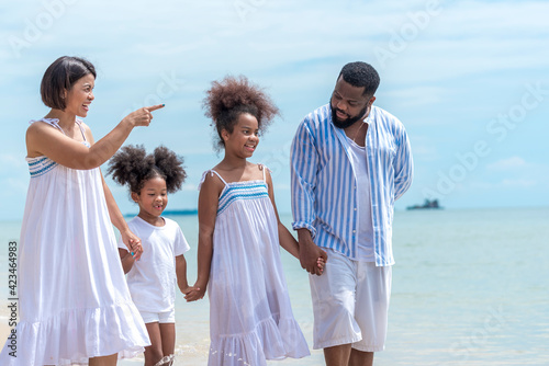 Happy African American family with African American father / asian mother and mixed race kids walking on the beach, thaliand photo