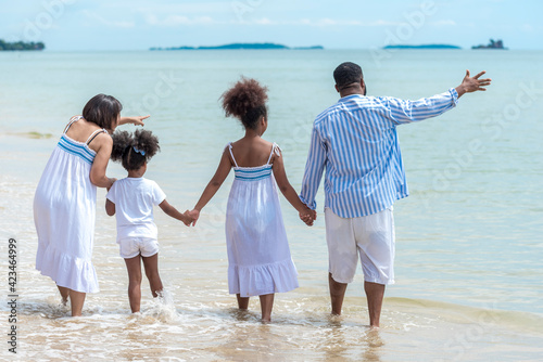 Happy African American family with African American father / asian mother and mixed race kids walking on the beach, thaliand photo