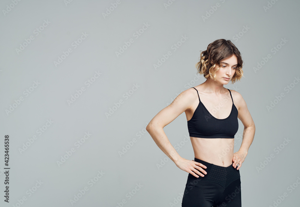 Woman in dark sportswear on gray background gesturing with hands cropped view Woman in dark sportswear on gray background gesturing with hands cropped view