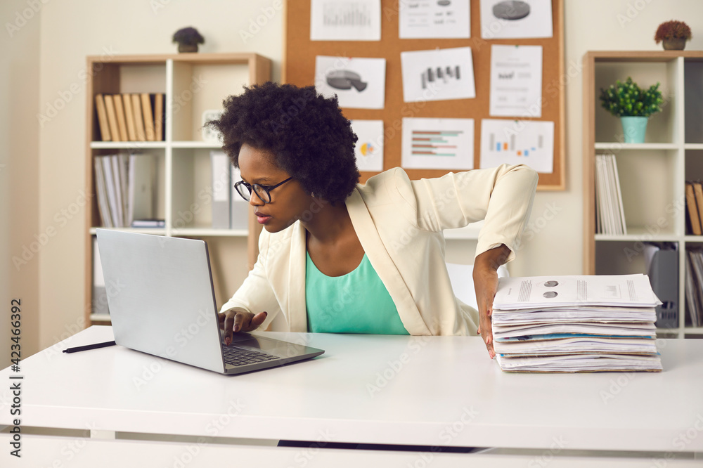 © Studio Romantic - Convenient electronic bookkeeping vs stacks of papers. Secretary or financial accountant organizing digital documents on computer. Young woman sitting at office desk and doing paperwork on laptop