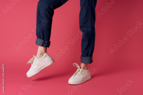 Fototapeta Naklejka Na Ścianę i Meble -  Female feet white sneakers street fashion pink background
