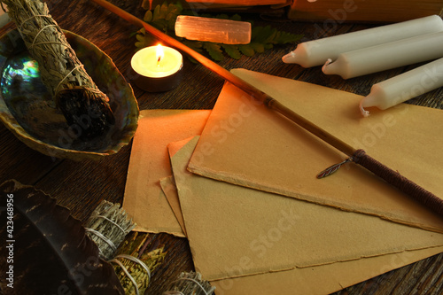 An image of several blank pages of paper with candles, sage, wand, and selenite. 