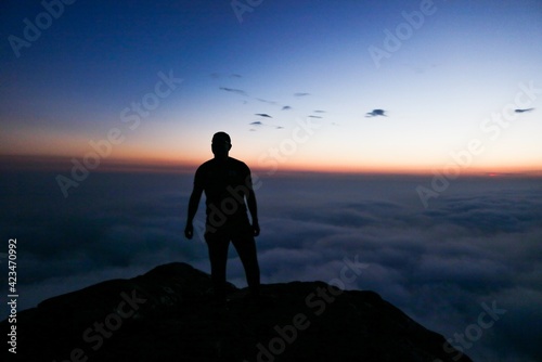 silhouette of man standing on top of mountain