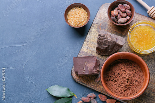 Cacao powder with beans, chocolate, honey and sugar on dark background