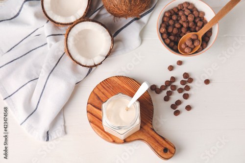 Jar of tasty coconut yogurt on light wooden background