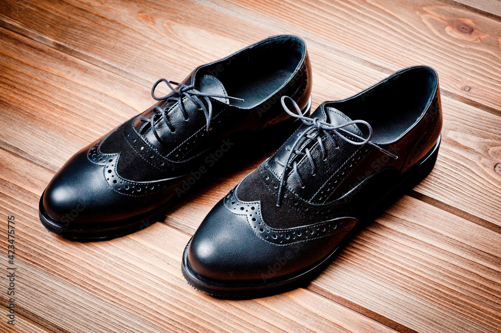 Black imitation leather shoes laced with wide laces. Close-up shot. Black imitation leather shoes laced with wide laces. Close-up shot.