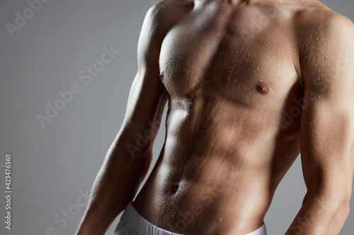 Foto portrait of a athletic man with a pumped-up torso on a gray background