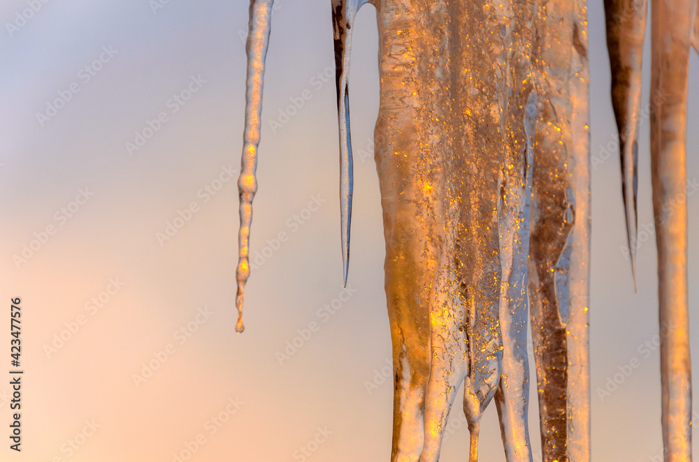 Hanging icicles on a background of setting sun and sunset sky. Hanging icicles on a background of setting sun and sunset sky.