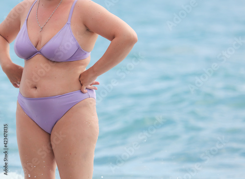 Fat woman in a swimsuit on the seashore. © schankz