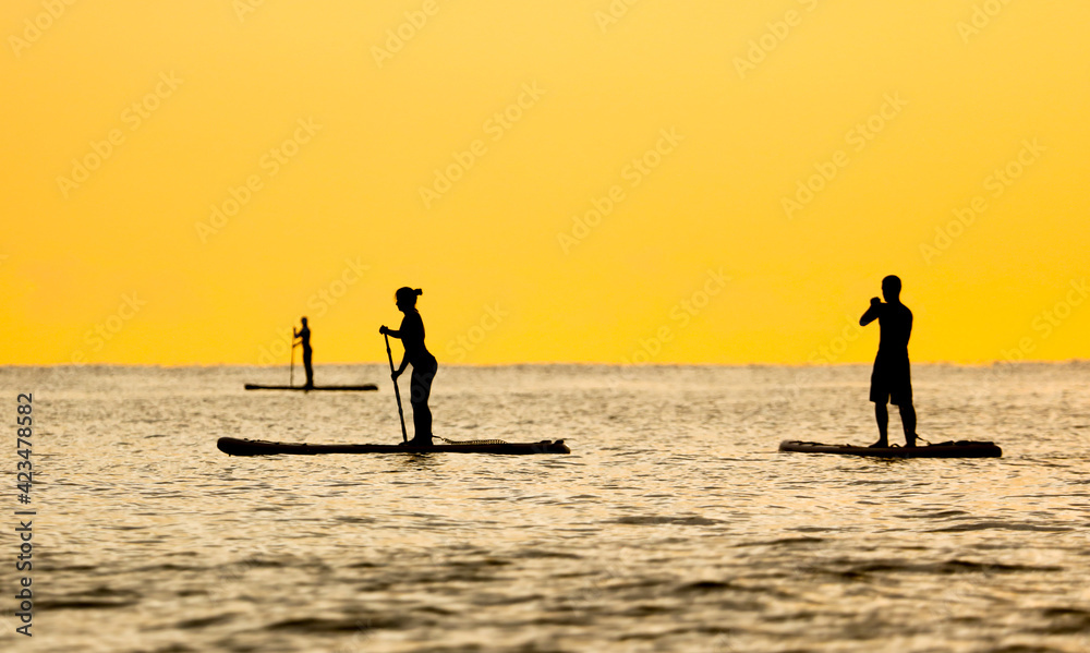 People on a board with a paddle float on the sea.